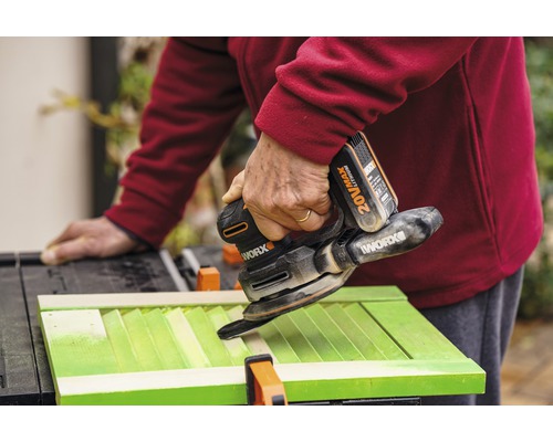 Handwerker schleift grüne Fensterläden mit einem Akku-Multischleifer von Worx