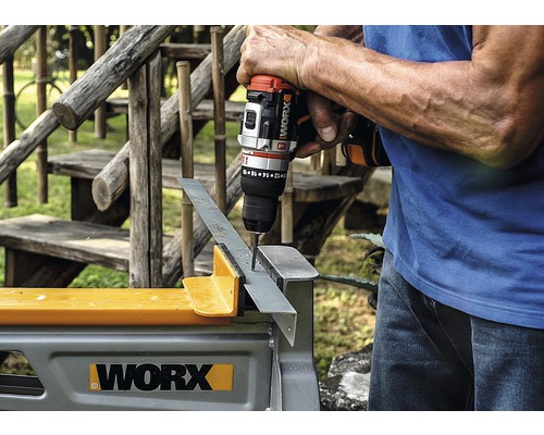 Eine Person bohrt mit einem Akku-Bohrschrauber ein Loch in ein Metallstück, das auf einer Werkbank liegt.