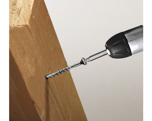 Ein Schraubendreher schraubt eine Schraube in ein Holzstück