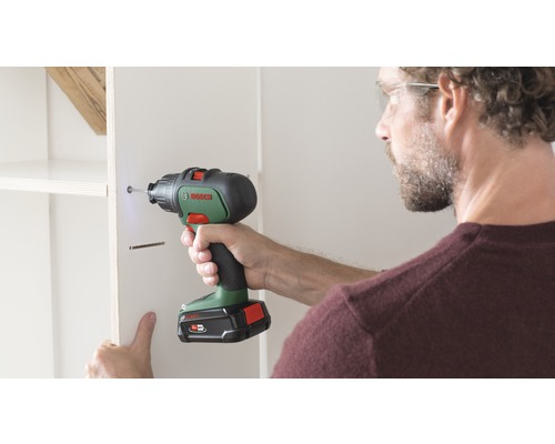 Handwerker befestigt ein Regal mit einem Akkuschrauber von Bosch