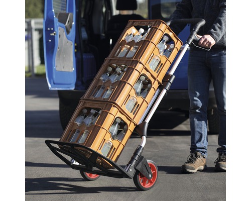 Eine Sackkarre transportiert Getränkekisten vor einem Fahrzeug.