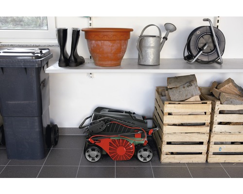Szene mit Mülltonne, Gummistiefeln, Blumentopf, Gießkanne, Kabeltrommel, Rasenmäher und Holzkisten im Lagerraum