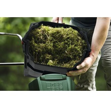 Person hält einen Behälter mit Grasschnitt über einen Gartengeräte