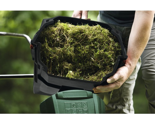 Person hält einen Behälter mit Grasschnitt über einen Gartengeräte