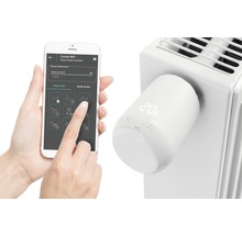 Intelligenter Heizkörperthermostat mit App-Steuerung am Heizkörper montiert und Smartphone zur Steuerung