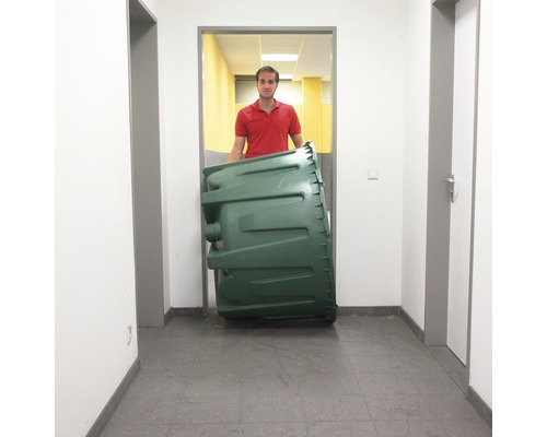 Eine Person transportiert einen grünen Kompostbehälter in einem Flur.