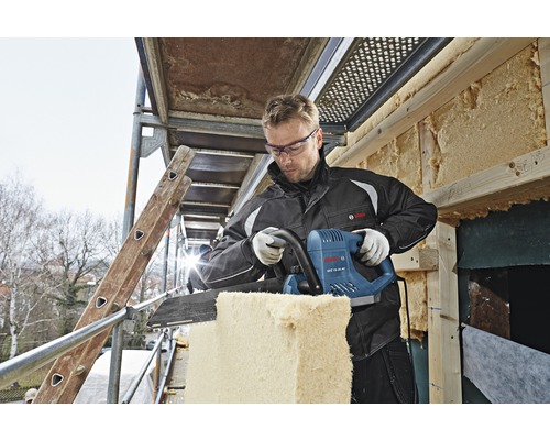 Ein Mann schneidet Dämmmaterial mit einer Dämmstoffsäge auf einem Gerüst. Bosch Logo.