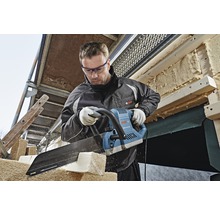 Ein Mann sägt mit einer Elektrosäge Holz auf einer Baustelle.