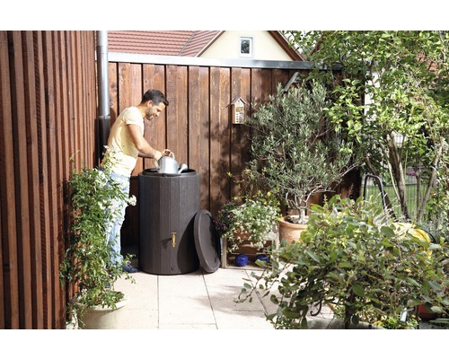 Szene im Garten mit Regentonne, Mann mit Gießkanne und Holzzaun