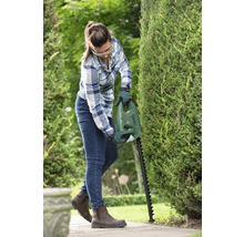 Frau schneidet Hecke mit Heckenschere von Bosch im Garten.