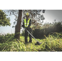 Eine Person mit Schutzhelm und Sicherheitsweste bedient einen Rasentrimmer im Freien.