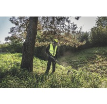 Ein Mann in Schutzkleidung arbeitet mit einem Rasentrimmer im Freien.