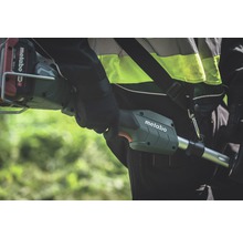 Eine Person trägt eine Metabo Akku-Motorsense über der Schulter.