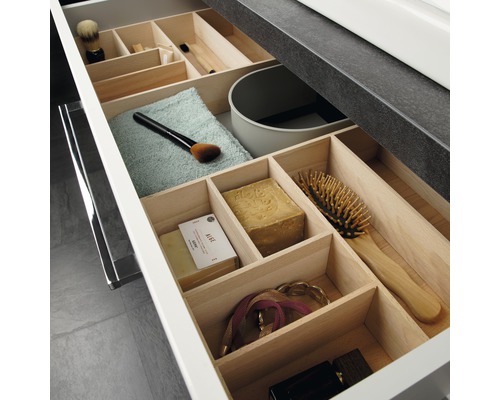 Offene Schublade mit Holzeinteilung und verschiedenen Badutensilien zur Aufbewahrung
