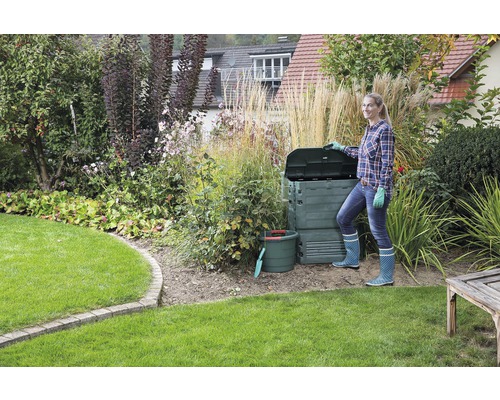 Gartenlandschaft mit Komposter, Gartengeräten und einer Frau
