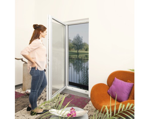 Frau betrachtet Insektenschutzgittertür in einem Wohnraum mit Blick auf einen See