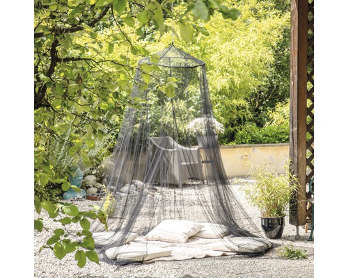 Moskitonetz im Garten mit Kissen und Decke auf Kiesboden