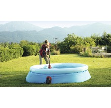 Frau benutzt eine Poolpumpe, um Wasser aus einem aufblasbaren Pool im Garten zu entfernen.