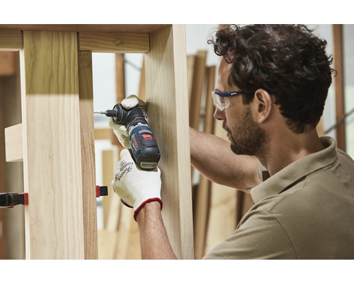 Ein Handwerker arbeitet mit einem Winkelbohrschrauber an einem Holzrahmen.