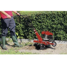 Person benutzt eine Gartenfräse im Garten.