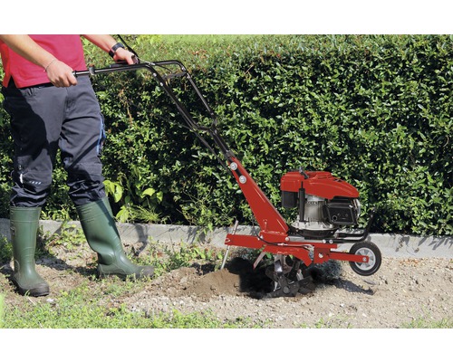 Person benutzt eine Gartenfräse im Garten.