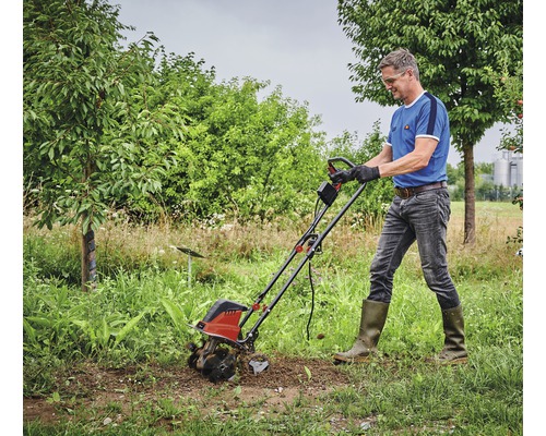 Mann arbeitet mit einer Motorhacke im Garten.