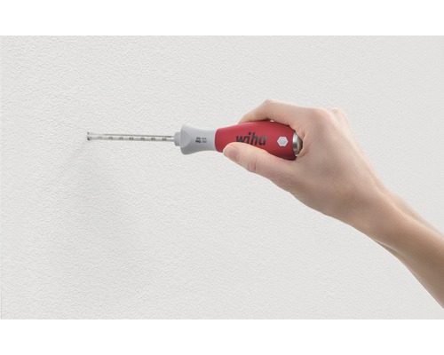 Eine Hand hält einen Tiefenanschlag-Schraubendreher von Wiha an einer Wand.