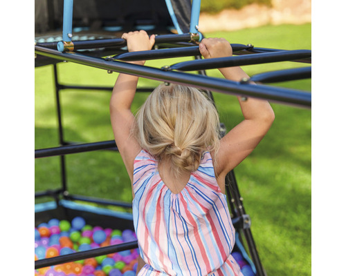 Kind klettert auf einer Klettergerüst-Spielanlage im Garten.