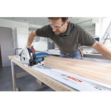 Mann sägt Holzbrett mit einer Bosch Tauchsäge und Führungsschiene.