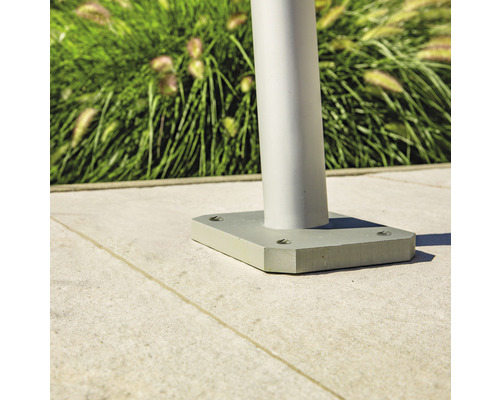 Detailansicht einer silberfarbenen Gartenleuchte mit quadratischer Basis auf einem Steinboden