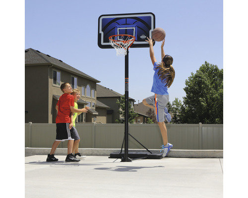 Szene mit transportablem Basketballkorb und Kindern beim Basketballspielen im Freien