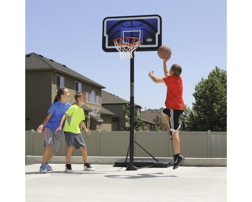 Kinder spielen Basketball auf einem tragbaren Basketballkorb im Freien.