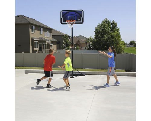Kinder spielen Basketball an einem Basketballkorb im Freien.
