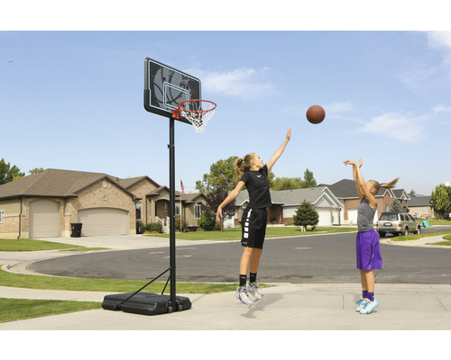 Zwei Mädchen spielen Basketball auf einem Basketballkorb im Freien