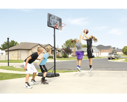 Kinder spielen Basketball auf einem Basketballplatz mit Basketballkorb.