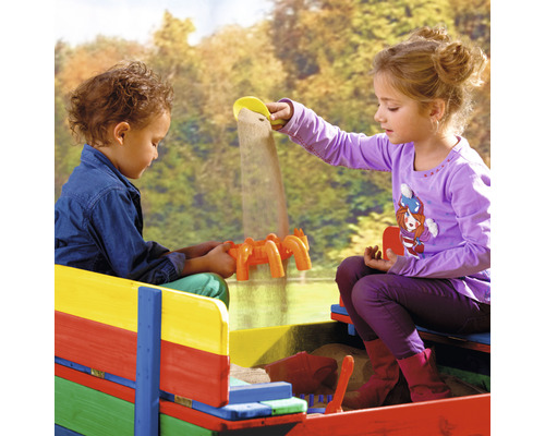 Zwei Kinder spielen in einem farbenfrohen Sandkasten mit Sandspielzeug.