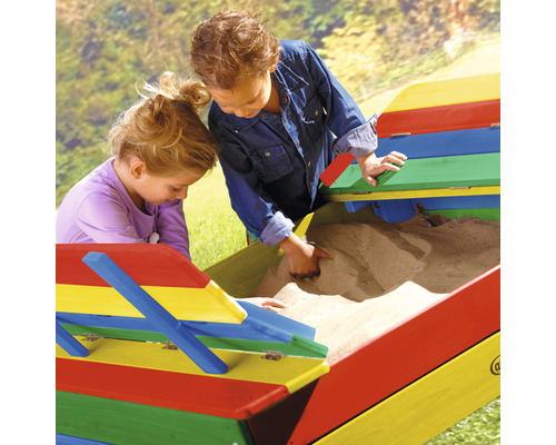 Zwei Kinder spielen in einem farbenfrohen Sandkasten mit Deckel