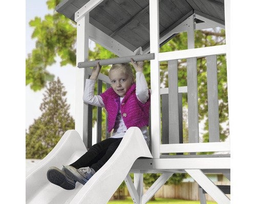 Mädchen auf einer Rutsche eines Spielturms im Garten.