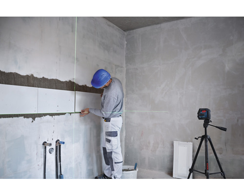 Handwerker verlegt Fliesen mit einem Kreuzlinienlaser auf einer Baustelle