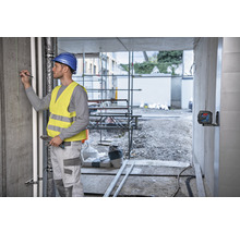 Handwerker mit Laser-Nivelliergerät auf einer Baustelle