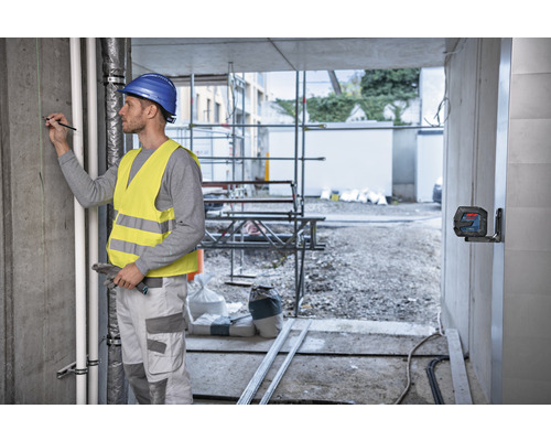 Handwerker mit Laser-Nivelliergerät auf einer Baustelle
