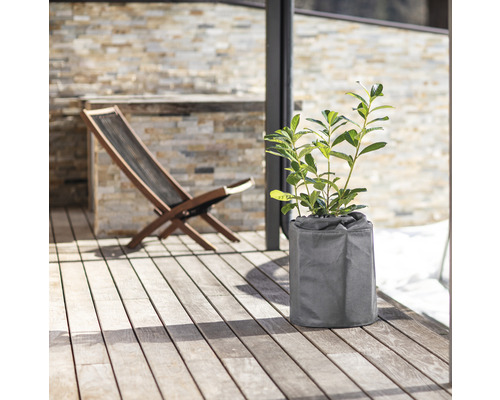 Außenszene mit Pflanze im Pflanzgefäß und Holzliegestuhl auf einer Terrasse