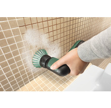 Eine Person reinigt Fliesen mit einer elektrischen Bürste.