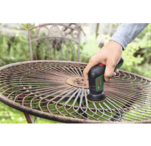 Eine Person reinigt einen Gartentisch aus Metall mit einem Schleifgerät von Bosch
