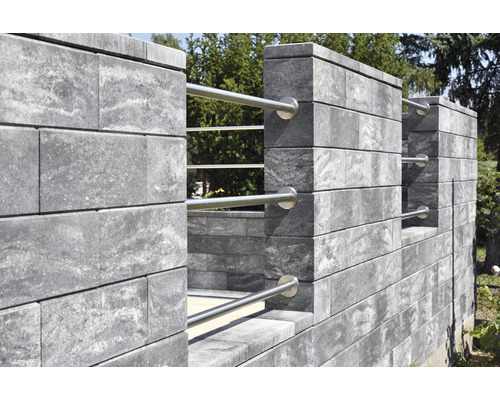 Graue Mauer aus Betonsteinen mit Metallelementen im Garten