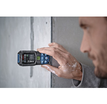 Mann misst Wand mit Laser-Entfernungsmesser von Bosch