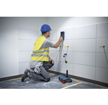 Handwerker nutzt ein Ortungsgerät an einer gefliesten Wand in einem Badezimmer.