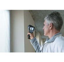 Mann verwendet eine Wärmebildkamera zur Inspektion einer Wand.