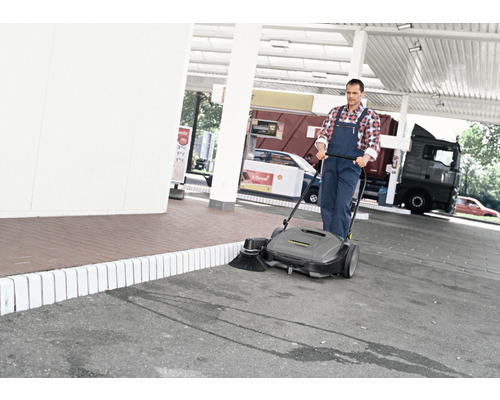 Mann kehrt mit einer Kehrmaschine einen Parkplatz