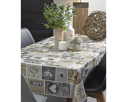 Gedeckter Tisch mit Tischdecke mit Herzmotiven und Dekorationsartikeln wie Kerzen und Pflanzen.